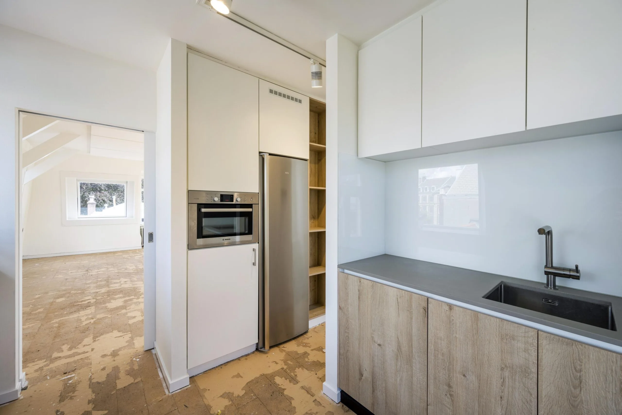 Moderne keuken in een appartement aan de Nieuwe Spiegelstraat met ingebouwde apparaten en houten onderkasten.