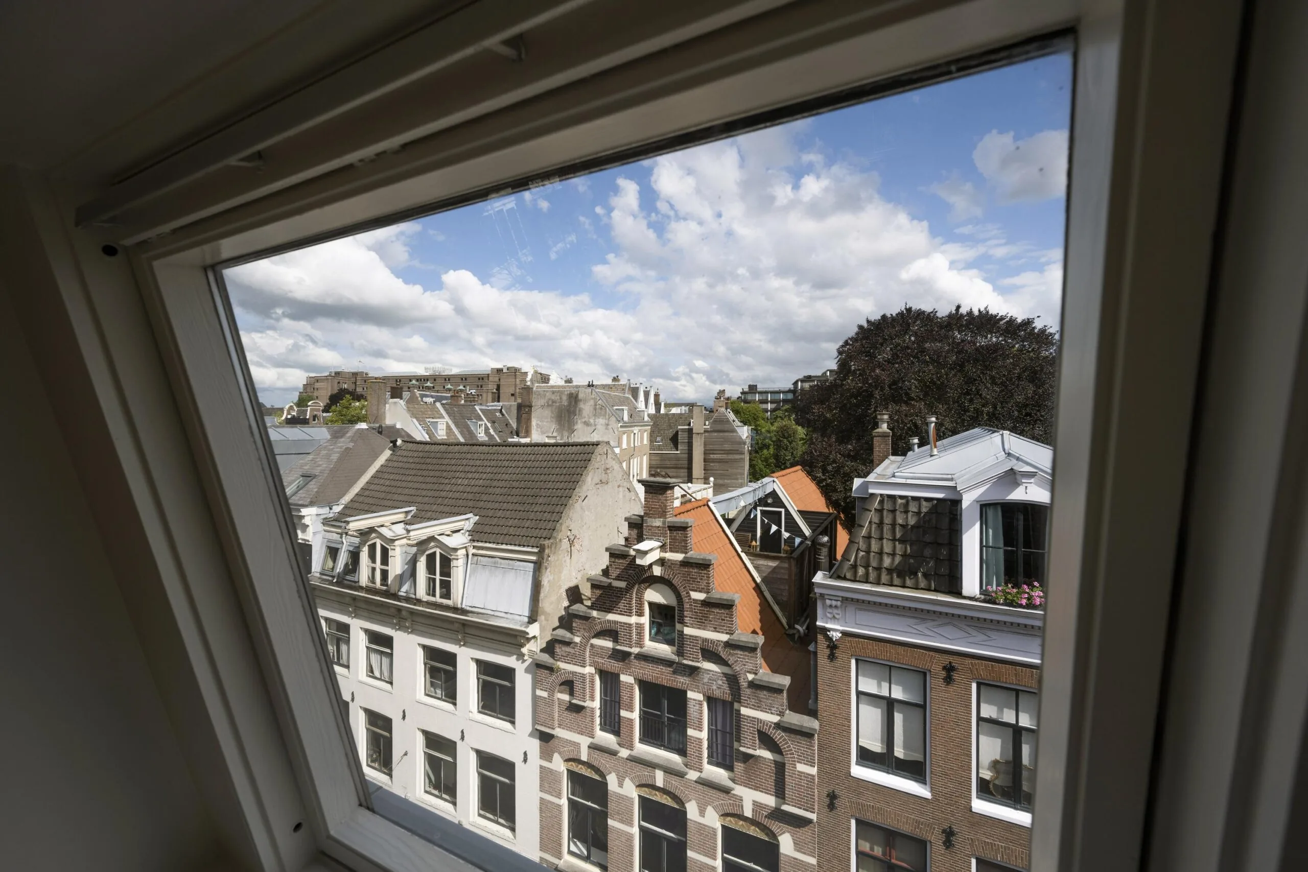 Uitzicht vanuit een dakraam op de gevels van historische panden aan de Nieuwe Spiegelstraat in Amsterdam.