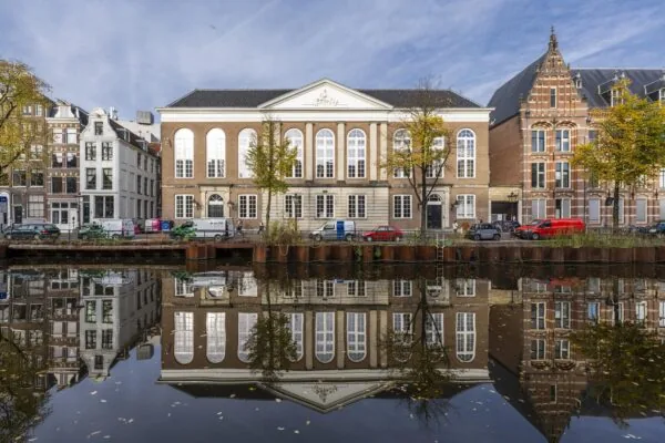 Gevels van historische panden aan de Kloveniersburgwal in Amsterdam weerspiegelen in het water van de gracht.
