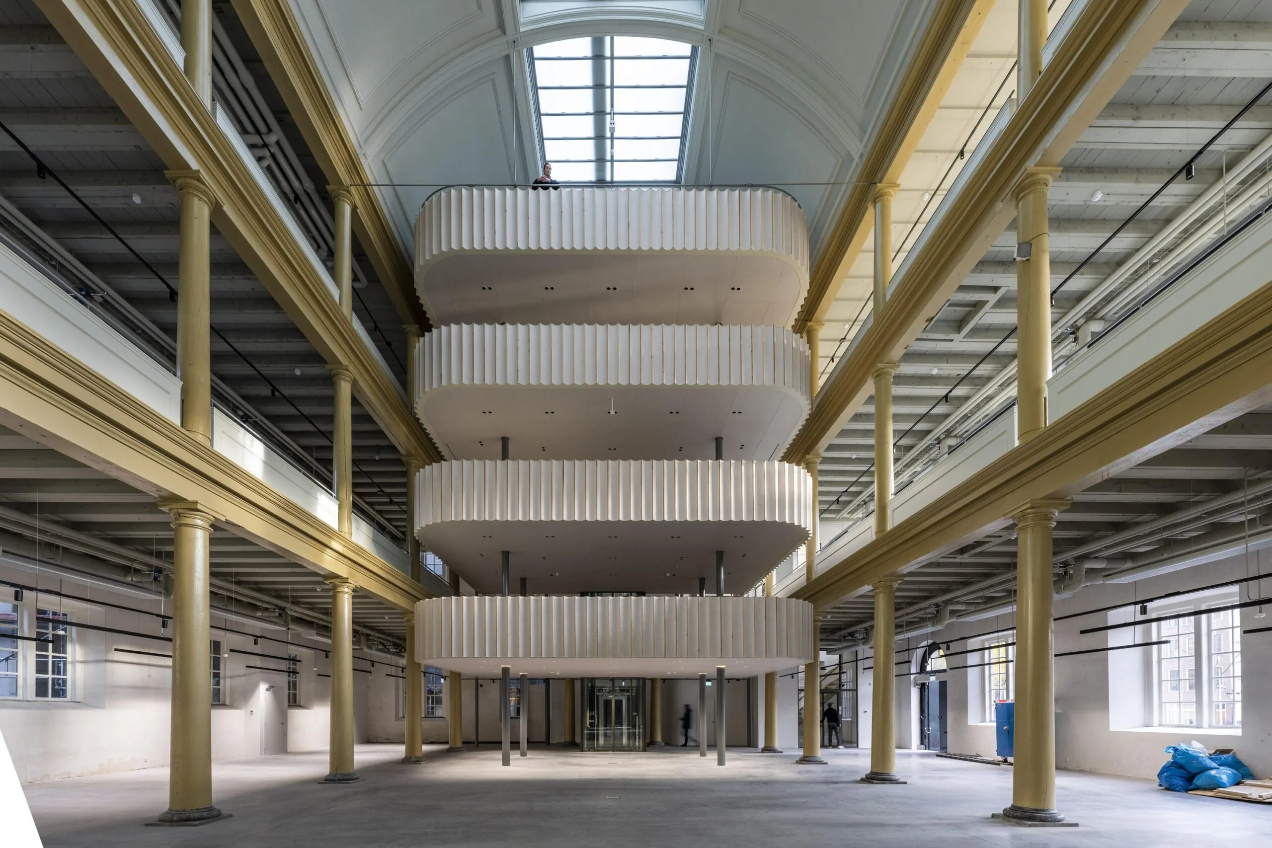 Interieur van het gerenoveerde gebouw aan de Kloveniersburgwal met een modern, centraal geplaatst balkonelement in een historische hal.