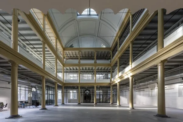 Licht en ruim atrium van het historische pand aan de Kloveniersburgwal met hoge plafonds, glazen dak en glazen wanden.