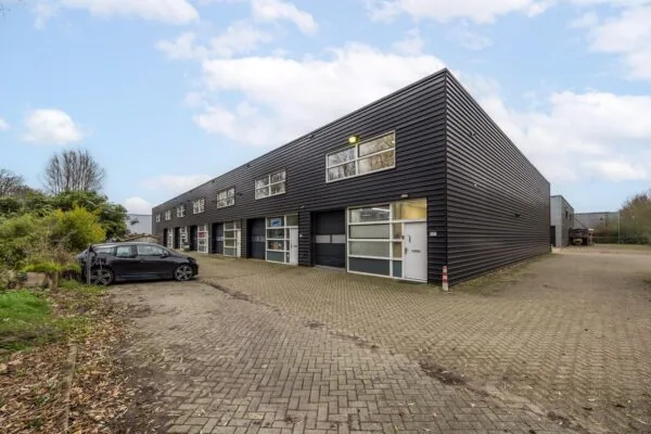 Zwart bedrijfsgebouw met meerdere units aan de Tennesseedreef, met een geparkeerde auto op de voorgrond.