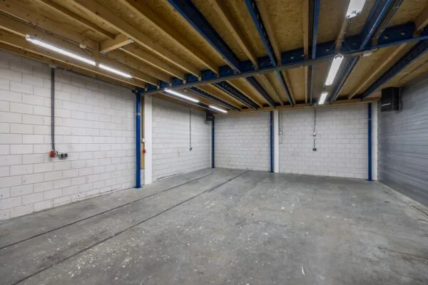Lege bedrijfshal aan de Tennesseedreef met betonnen vloer, witte stenen muren en zichtbare plafondconstructie.