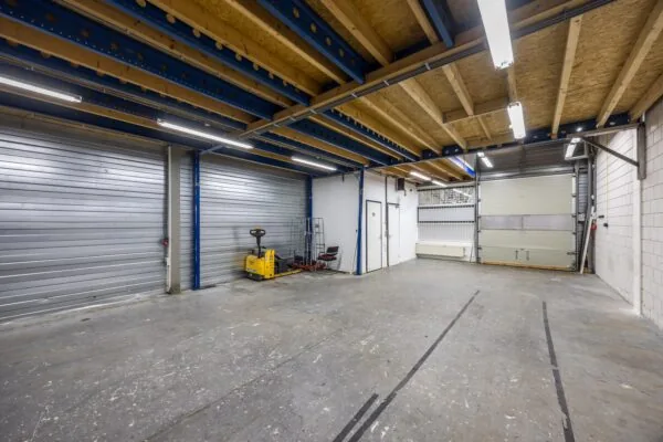 Magazijnruimte aan de Tennesseedreef met betonnen vloer, overheaddeuren en palletwagen.