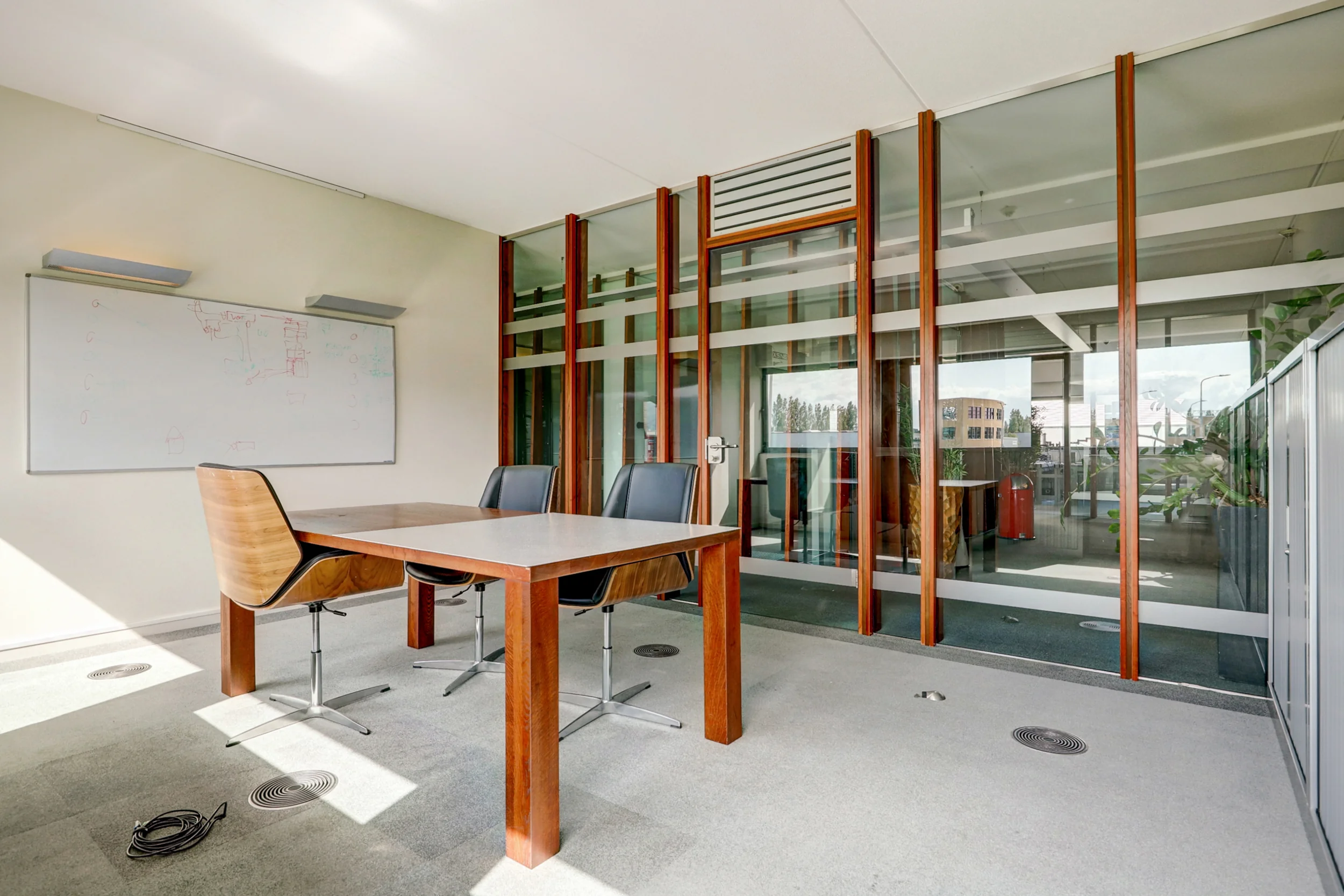 Moderne vergaderruimte met glazen wanden, houten tafel, vier stoelen en een whiteboard aan de muur in een kantoor aan de New Yorkstraat.