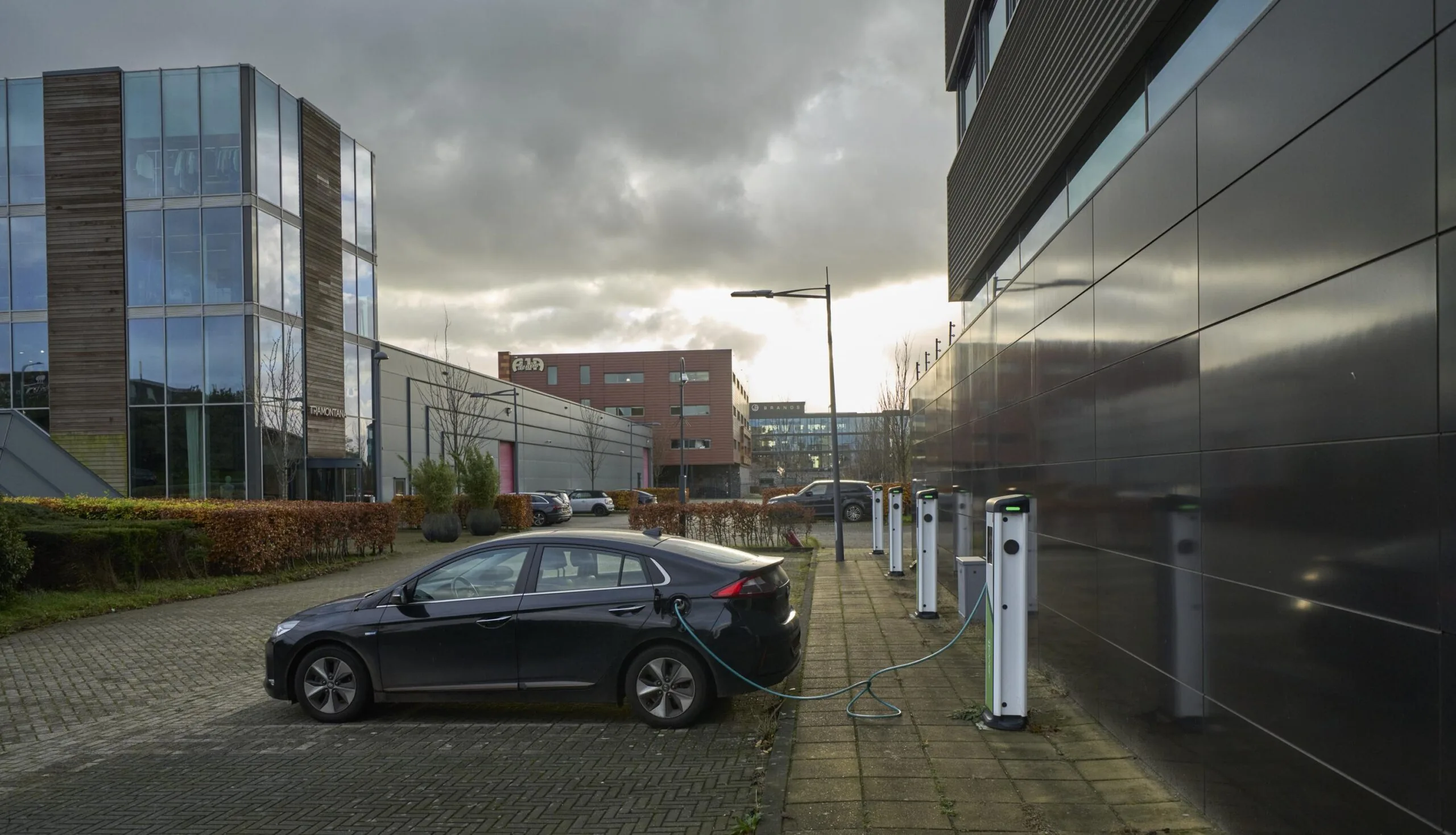 Een elektrische auto laadt op bij een laadpaal op een bedrijventerrein aan de New Yorkstraat.