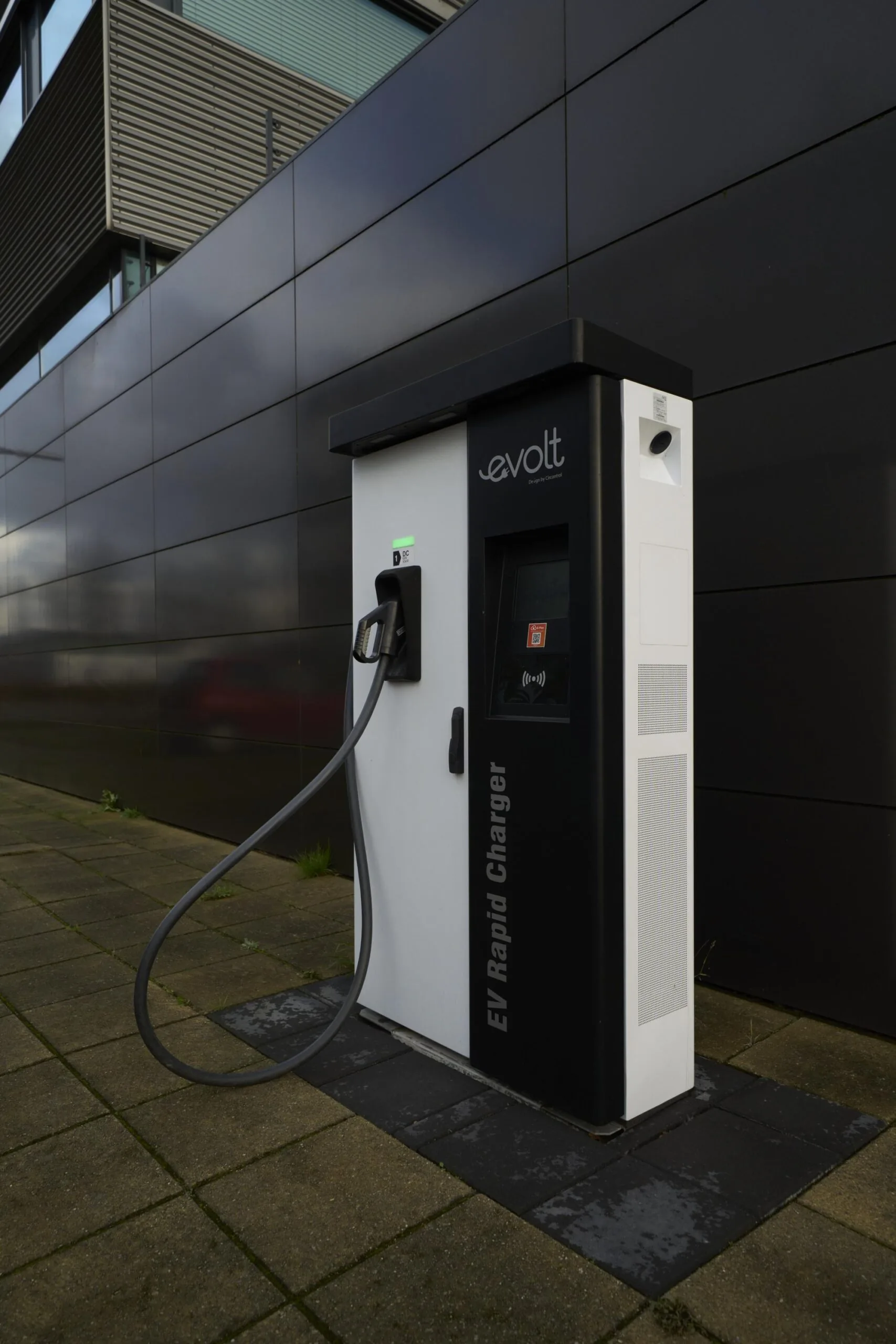 Elektrische oplaadpaal van het merk Evolt naast een modern gebouw in een straat in New York.