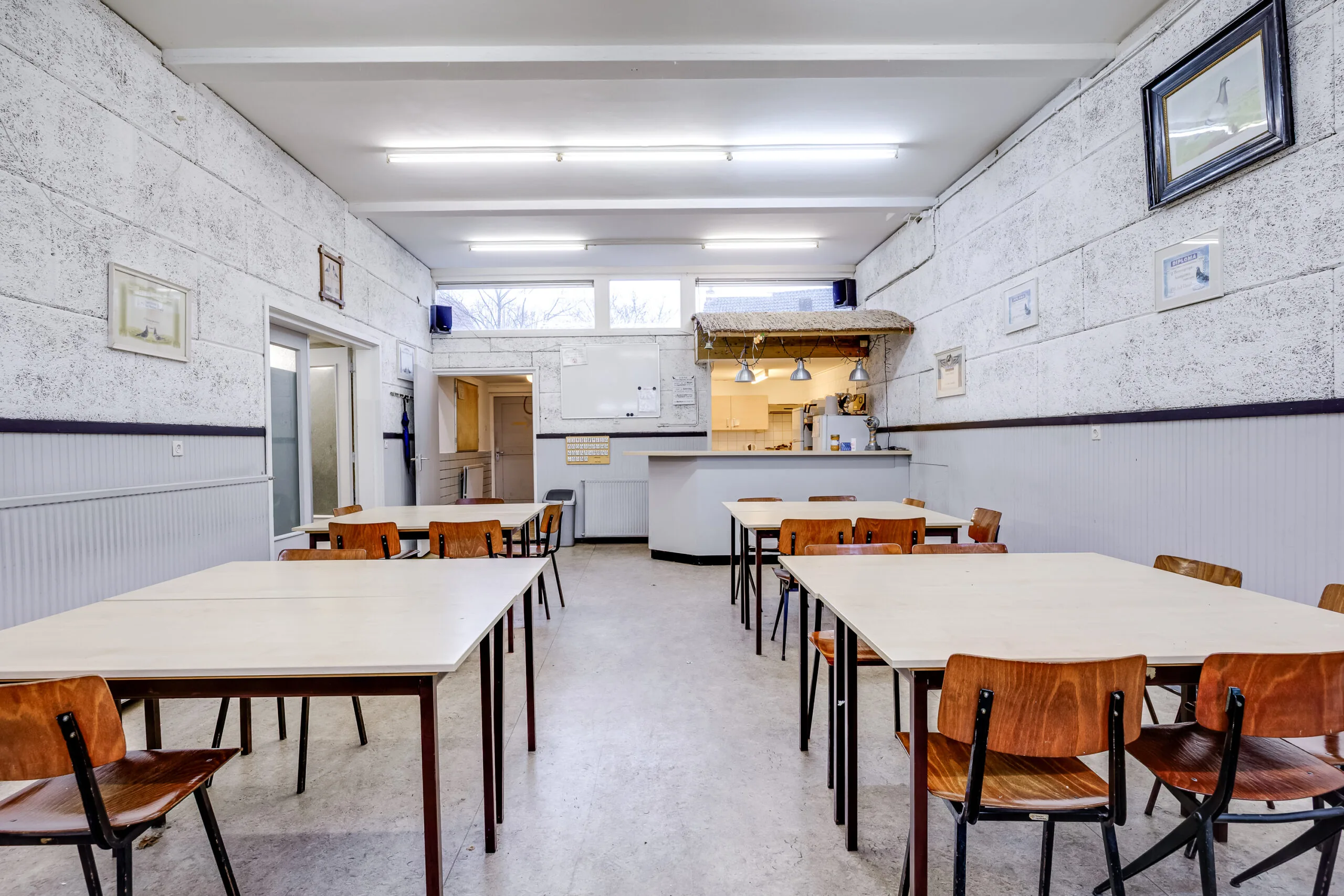 Eenvoudige gemeenschappelijke ruimte met tafels en stoelen, een bar en decoratie aan de muren in de Balderikstraat.