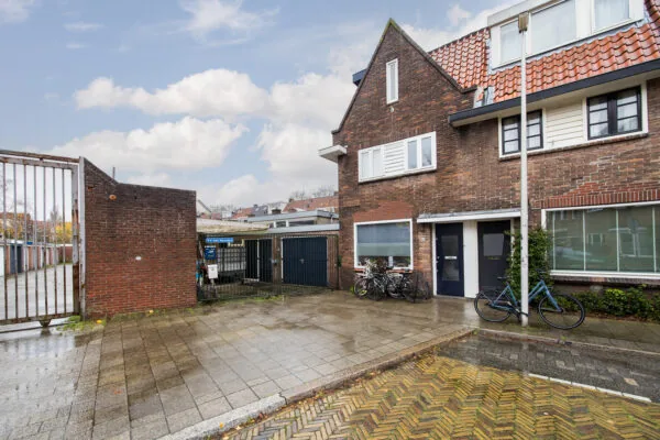 Vooraanzicht van een rijtjeshuis aan de Balderikstraat met fietsen voor de deur en een poort naar een binnenterrein.