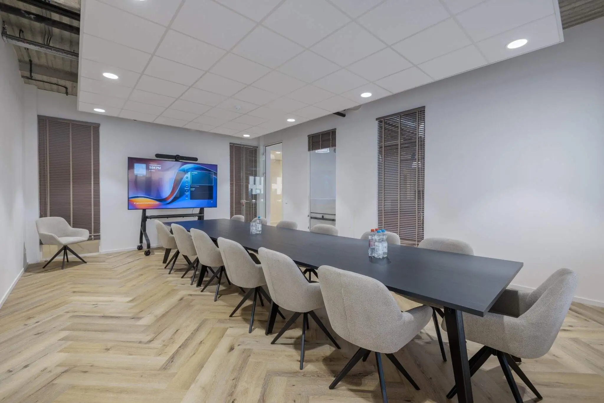 Moderne vergaderruimte met lange tafel en stoelen, voorzien van een groot scherm.