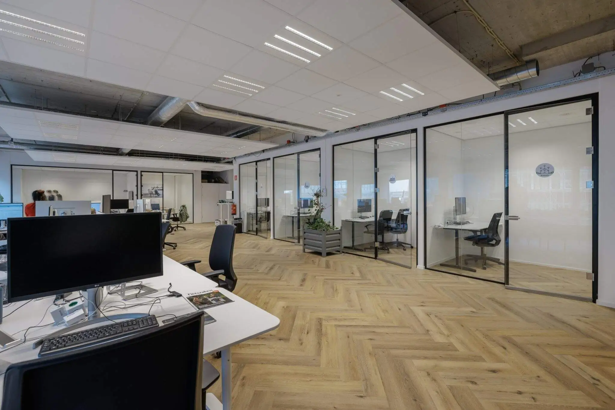 Moderne kantoorruimte met glazen vergaderruimtes en houten vloer aan de Joan Muyskenweg.