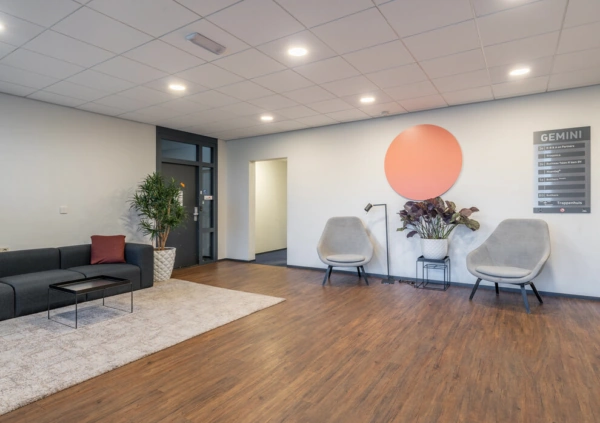 Moderne wachtruimte aan de K.P. van der Mandelelaan met zitgelegenheid, planten en wegwijsbord van het Gemini-gebouw.