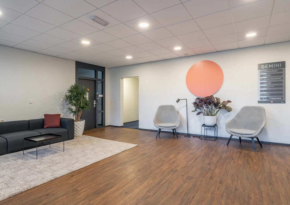 Moderne wachtruimte aan de K.P. van der Mandelelaan met zitgelegenheid, planten en wegwijsbord van het Gemini-gebouw.