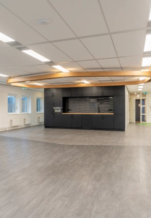Moderne open ruimte met een zwarte kitchenette en houten plafondaccent aan de K.P. van der Mandelelaan.