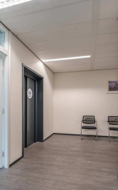 Wachtkamer met zwarte stoelen en een liftdeur aan de K.P. van der Mandelelaan.