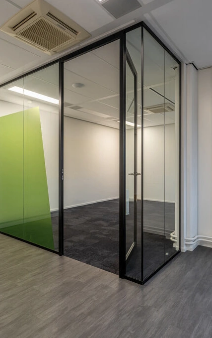 Moderne glazen kantoorruimte aan de K.P. van der Mandelelaan met zwart metalen kozijnen en groene wanddecoratie.