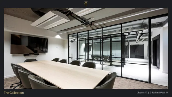 Moderne vergaderruimte aan de Stadhouderskade 85 met glazen wanden, een houten vergadertafel en een groot presentatiescherm.
