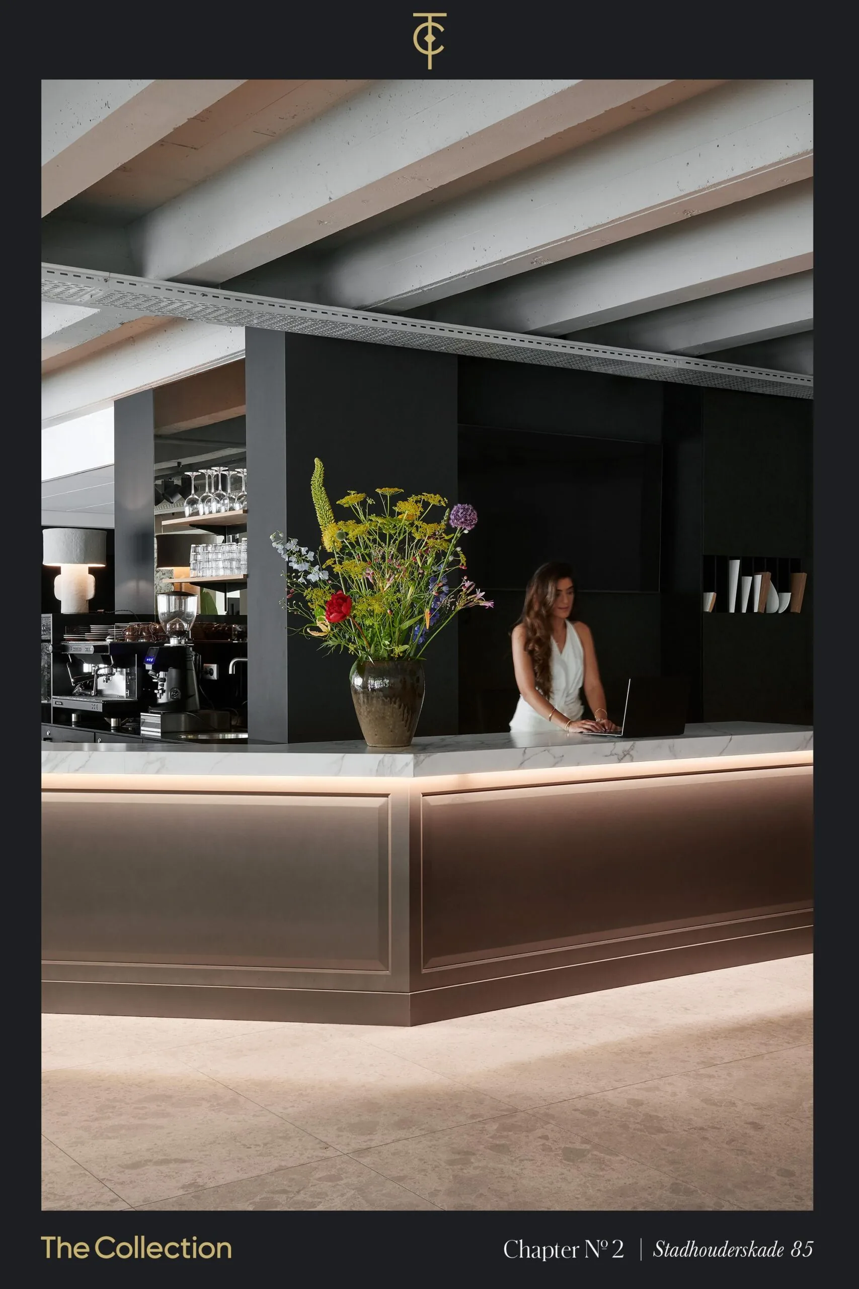 Vrouw werkt op een laptop achter een moderne ontvangstbalie met een bloemenvaas bij Stadhouderskade 85.