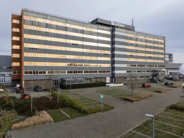 Kantoorgebouw Westlake aan de Seattleweg met reflecterende ramen en een grotendeels lege parkeerplaats.