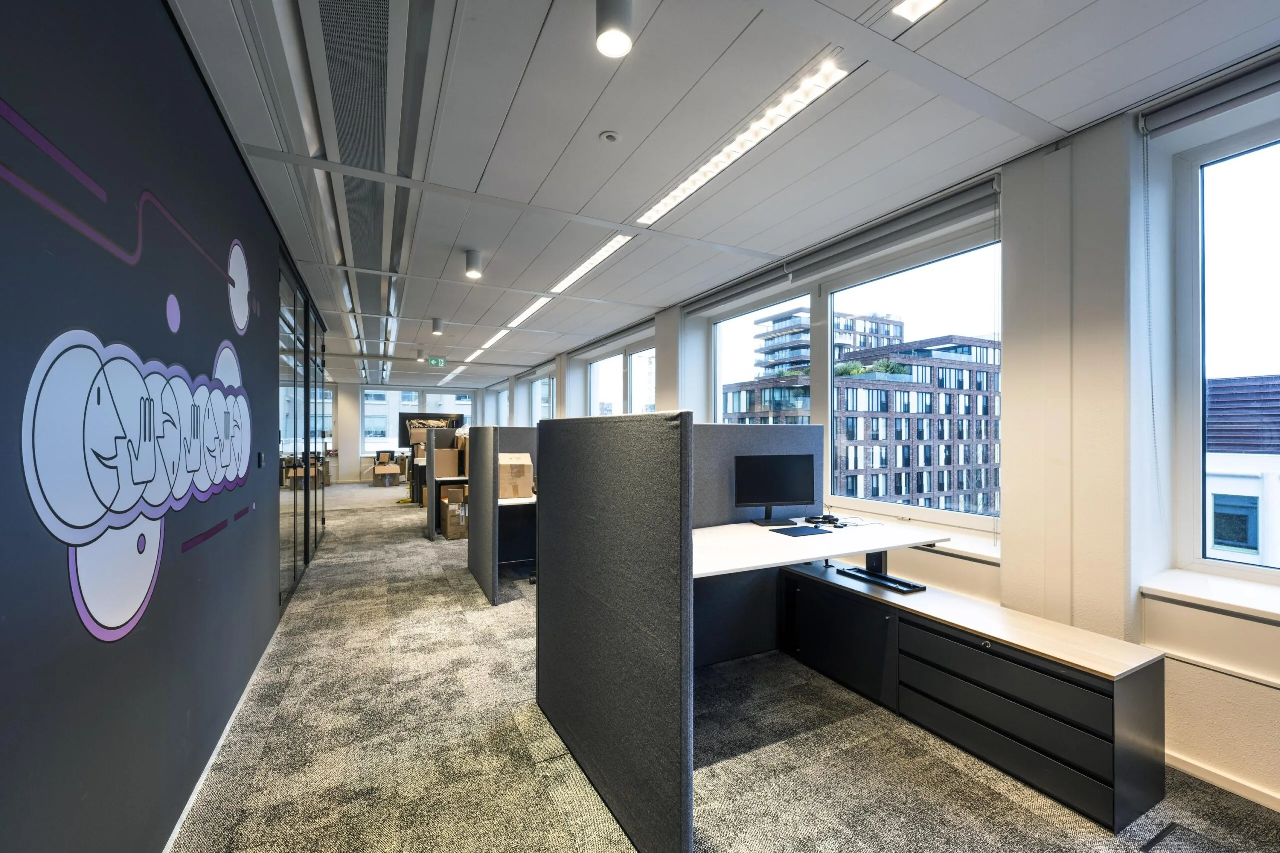 Moderne kantoortuin met werkplekken, uitzicht op een stad en een muurdecoratie met het woord "Stroombaan".