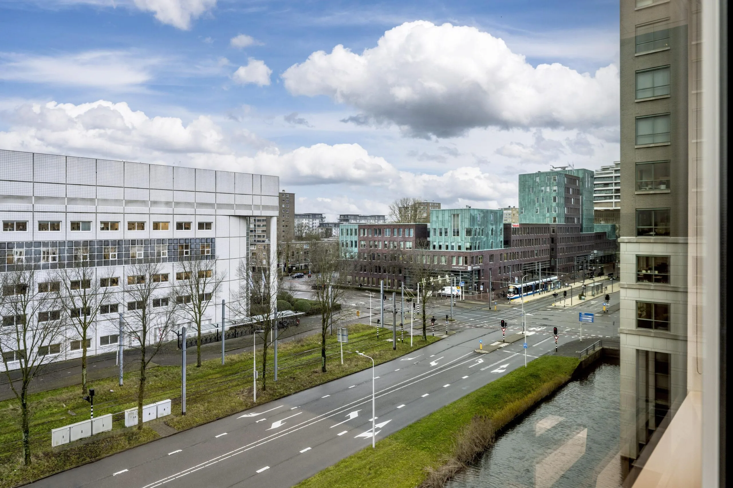 Stadsgezicht op de Stroombaan in Amstelveen met moderne gebouwen, een trambaan en een kruispunt.