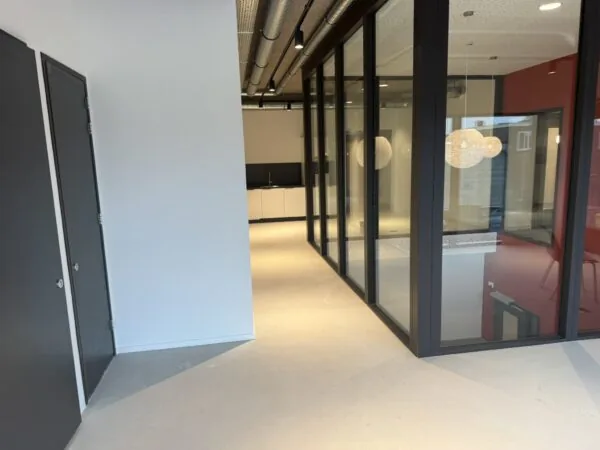 Moderne kantoorruimte aan de Saturnusstraat met glazen wanden, hanglampen en een kitchenette op de achtergrond.