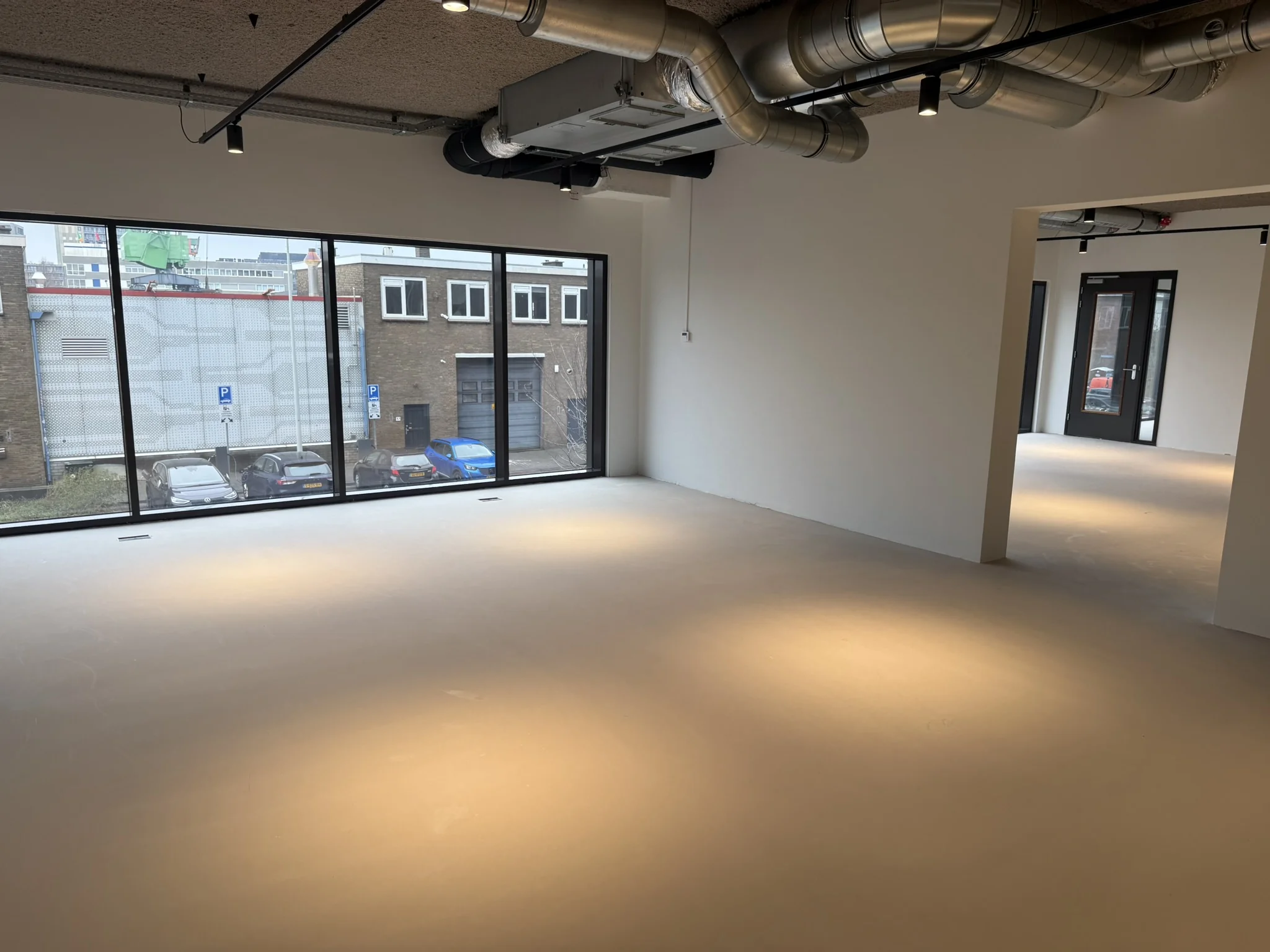 Licht industrieel ogende kantoorruimte aan de Saturnusstraat met grote ramen en zichtbaar ventilatiesysteem.