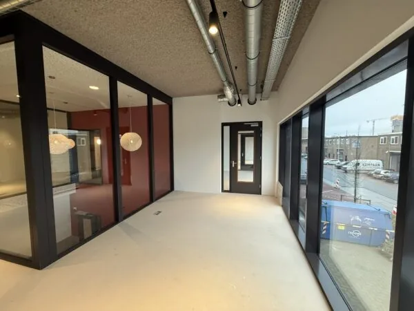 Leeg kantoorpand aan de Saturnusstraat met grote ramen, zicht op de straat en een aparte vergaderruimte met glazen wanden.