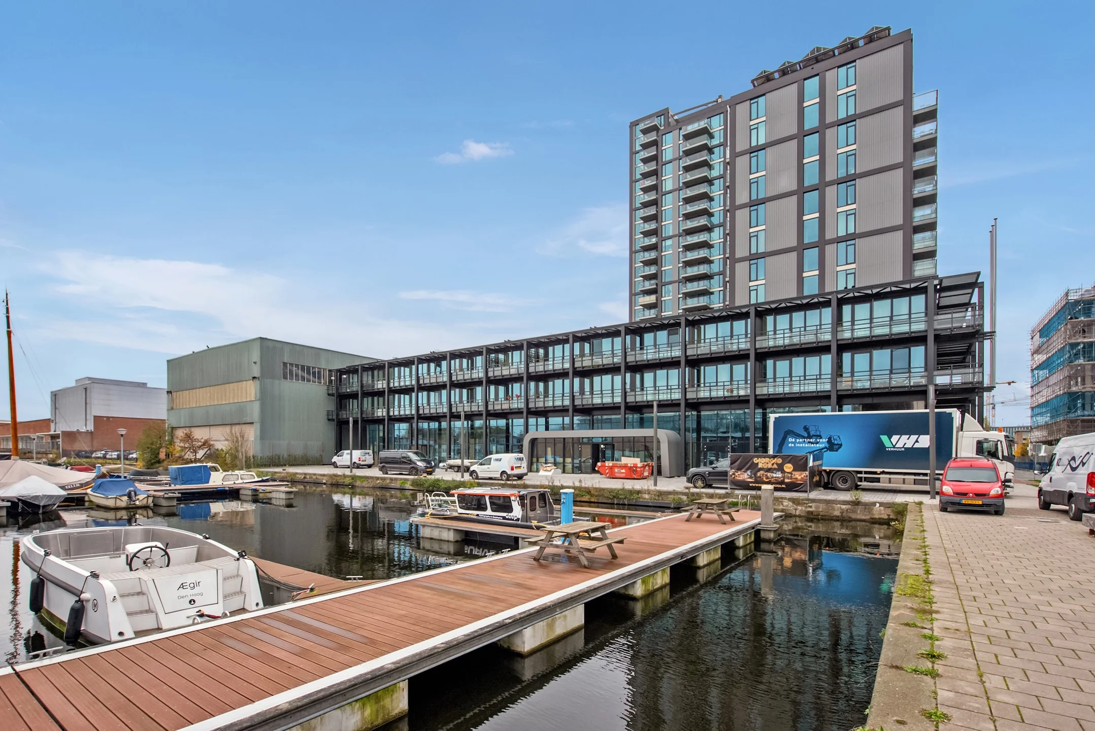 Modern kantoorgebouw aan de Saturnusstraat met uitzicht op een jachthaven en aanlegsteiger.