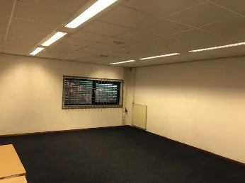 Lege kantoorruimte aan de Euclideslaan met witgeschilderde muren, systeemplafond en een raam met tralies.