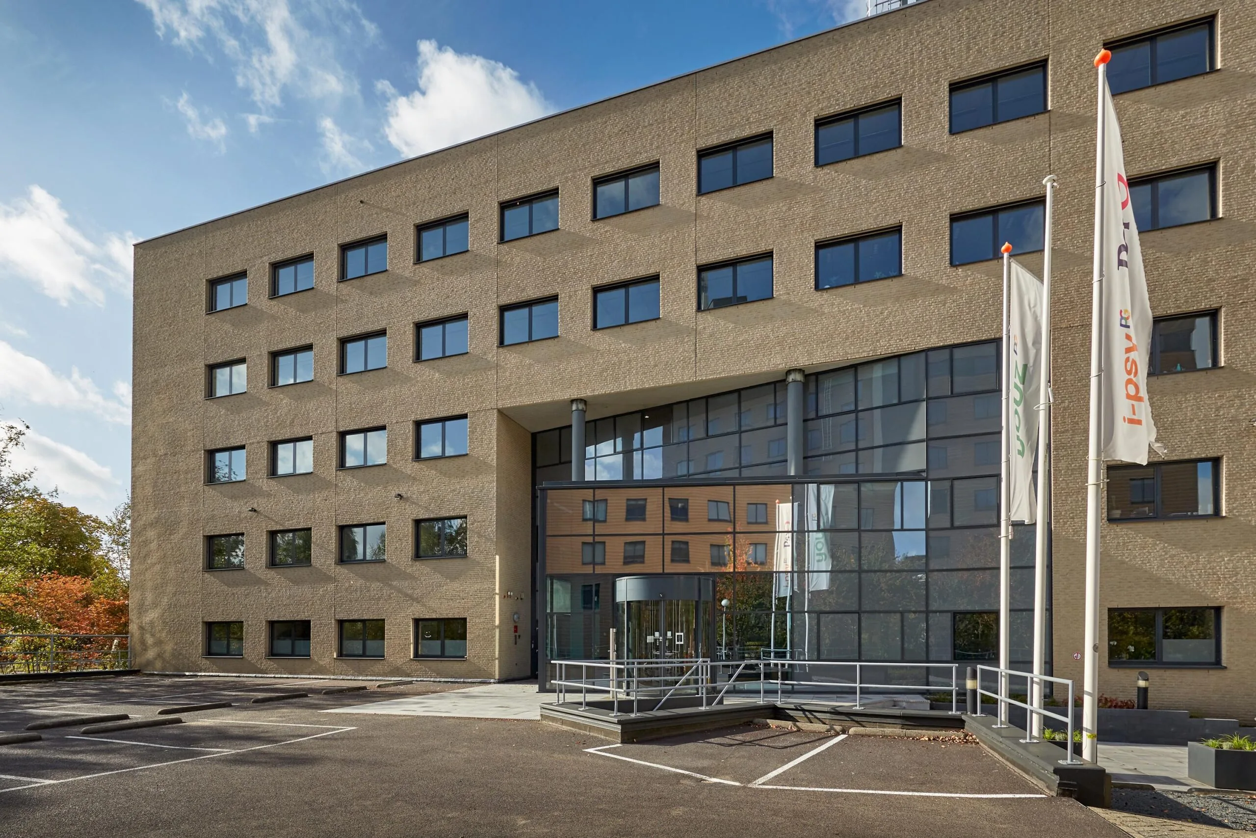 Vooraanzicht van een modern kantoorgebouw aan de Euclideslaan met vlaggen en parkeergelegenheid.
