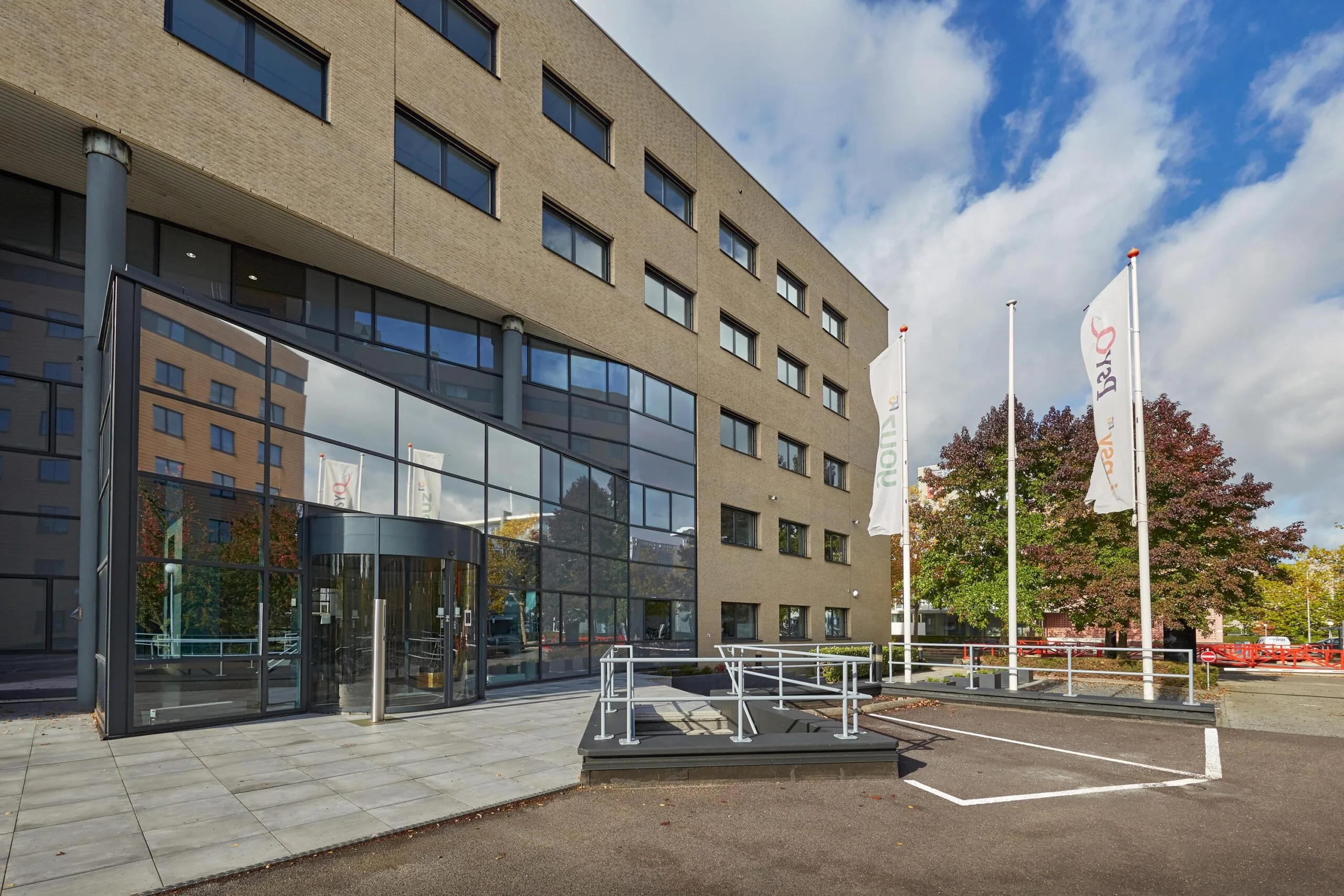 Voorgevel van een modern kantoorgebouw aan de Euclideslaan met glasentree, vlaggenmasten en toegankelijkheidsvoorzieningen.