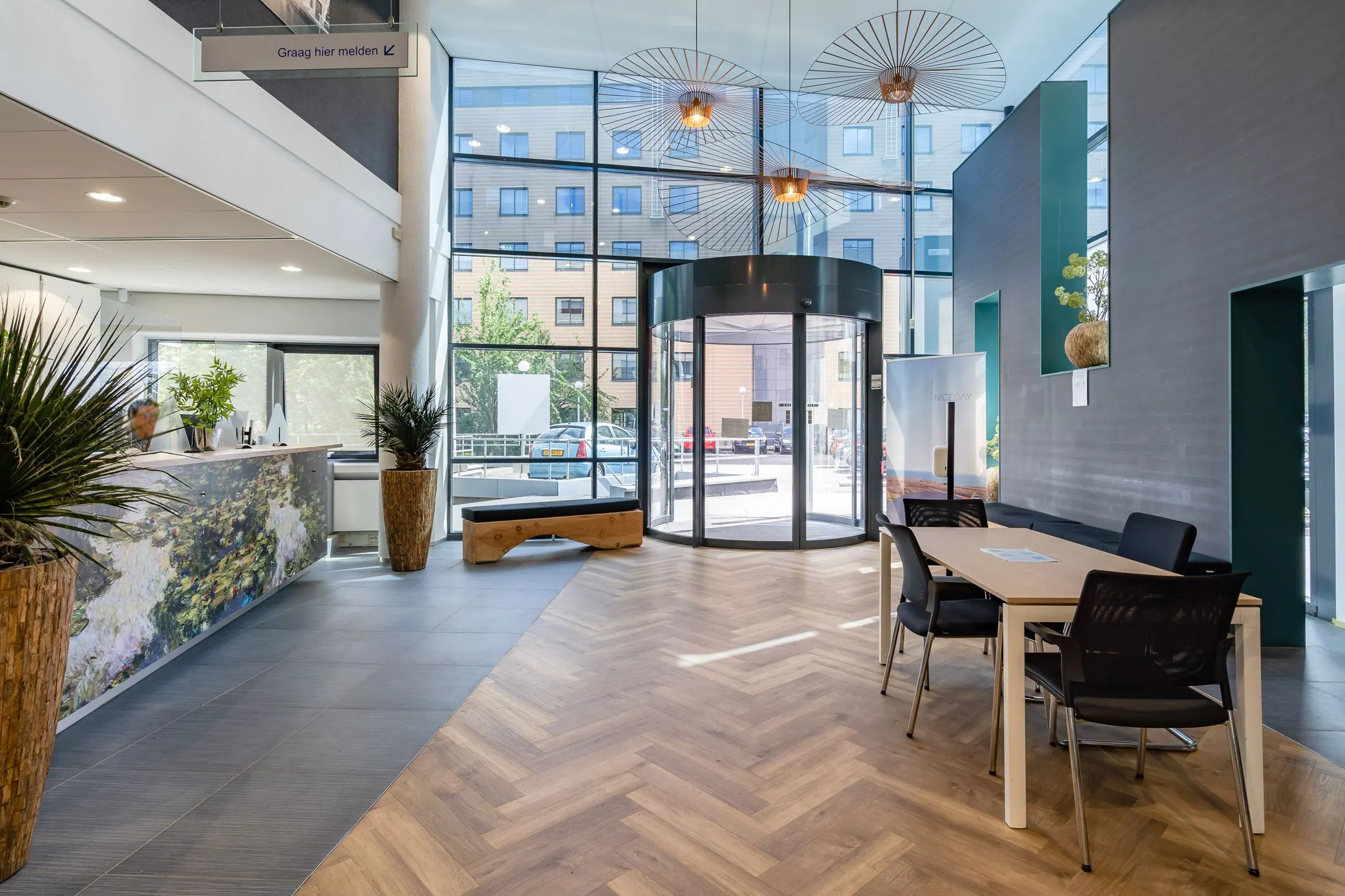 Moderne en lichte entreehal van een kantoorgebouw aan de Euclideslaan met een receptiebalie, wachtruimte en draaideur.
