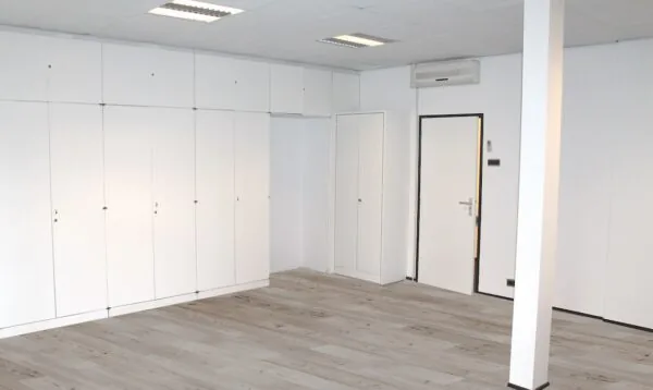 Lege kamer met witte kastenwand, deur en airconditioning aan het plafond.