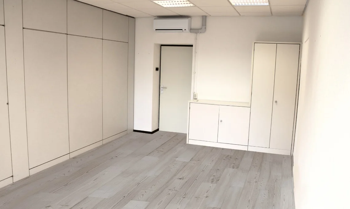 Een lege, lichte kamer met ingebouwde kasten en een deur.