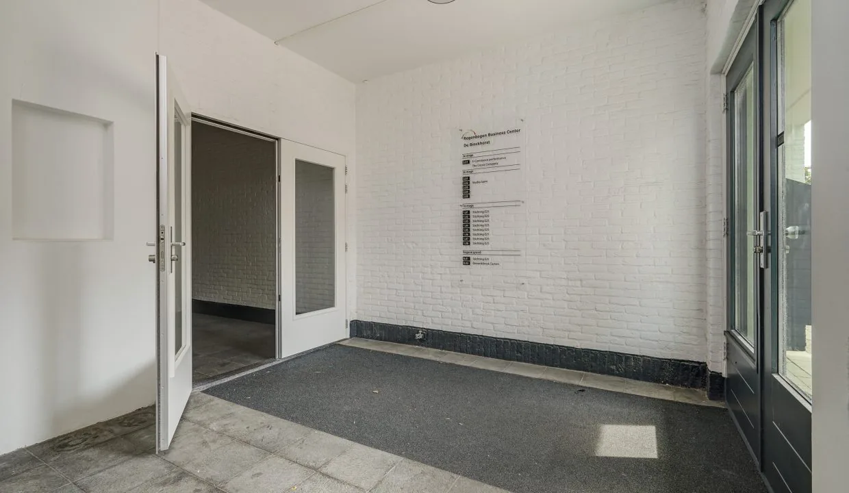 Ingang van een bedrijfsverzamelgebouw aan de Mercuriusweg met witte muren, glazen deuren en een bord met bedrijfsnamen.