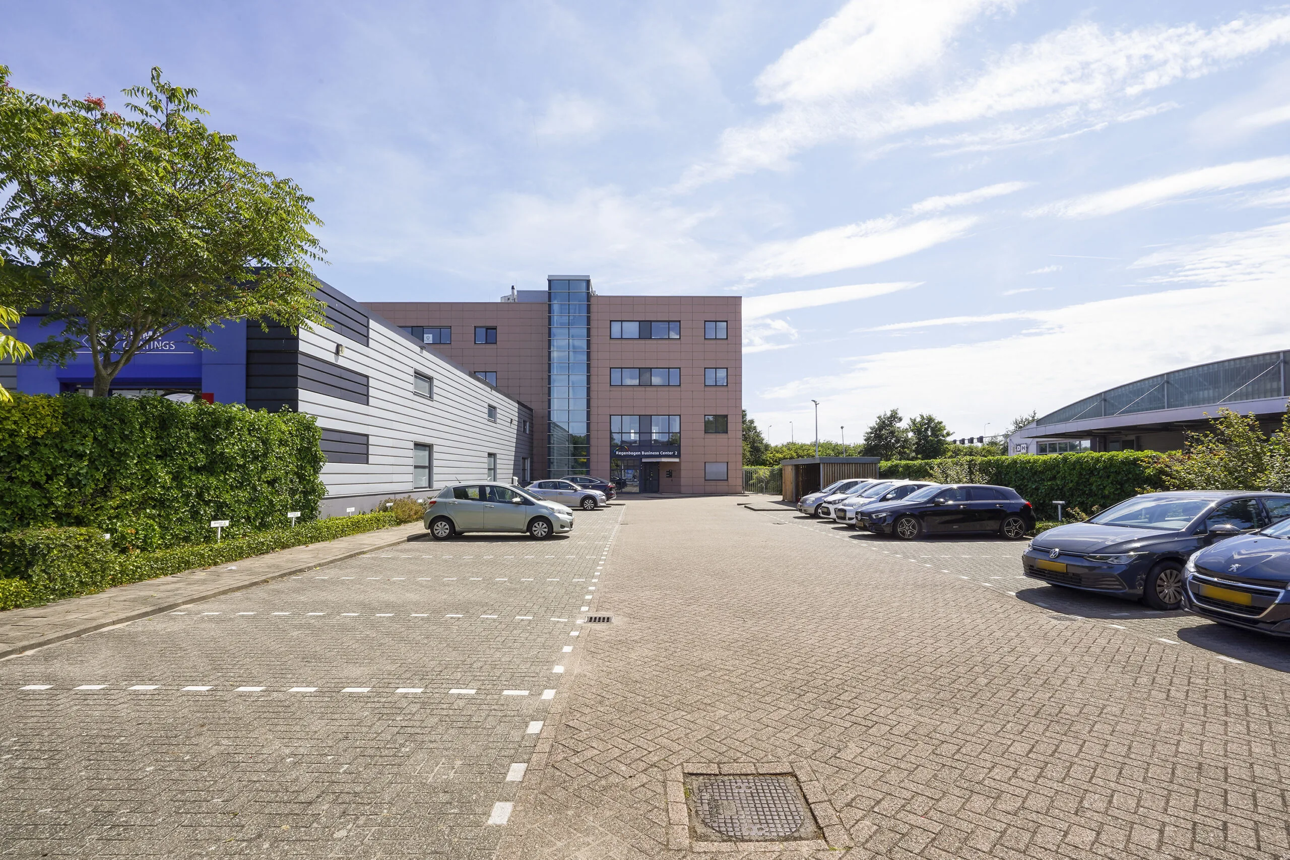 Parkeerterrein met geparkeerde auto's voor het kantoorgebouw aan de Laan van ’s-Gravenmade.
