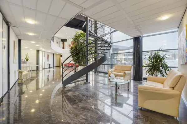 Moderne en lichte kantoorentree aan de Laan van ’s-Gravenmade met glazen gevel, wenteltrap en zithoek.