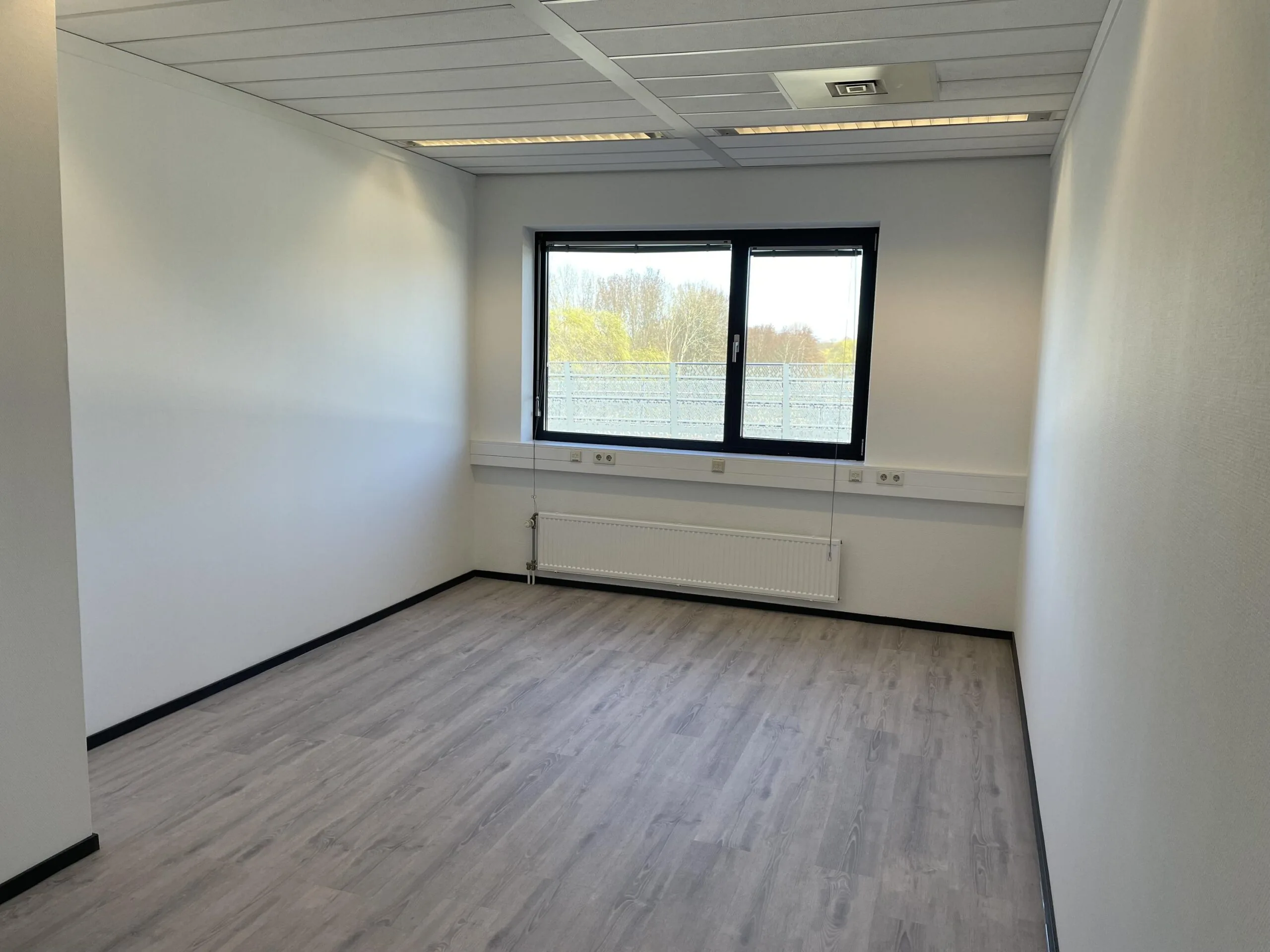 Lege kantoorruimte met laminaatvloer en groot raam aan de Laan van ’s-Gravenmade.