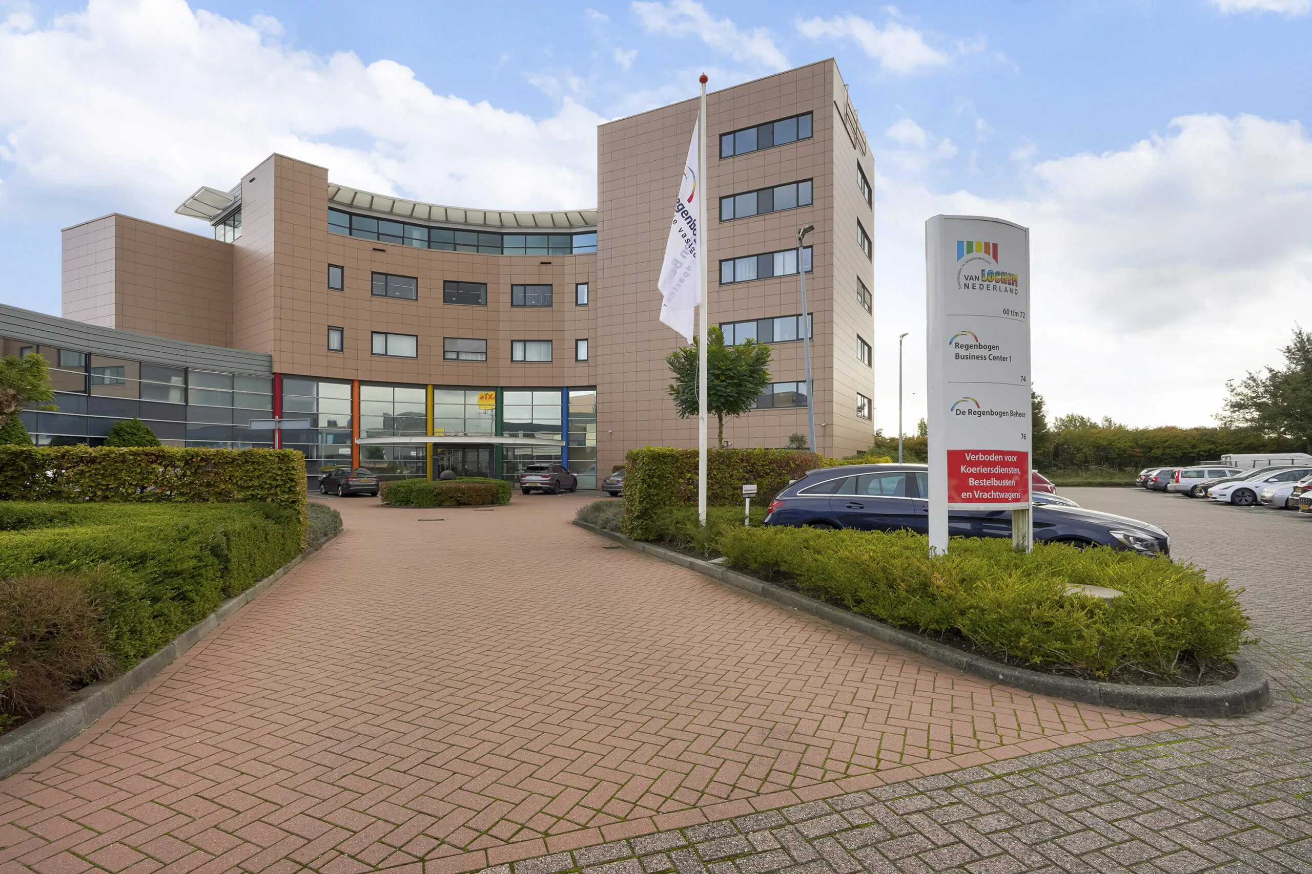 Ingang van het Regenbogen Business Center aan de Laan van ’s-Gravenmade met parkeerplaats en bedrijfsnaambord.