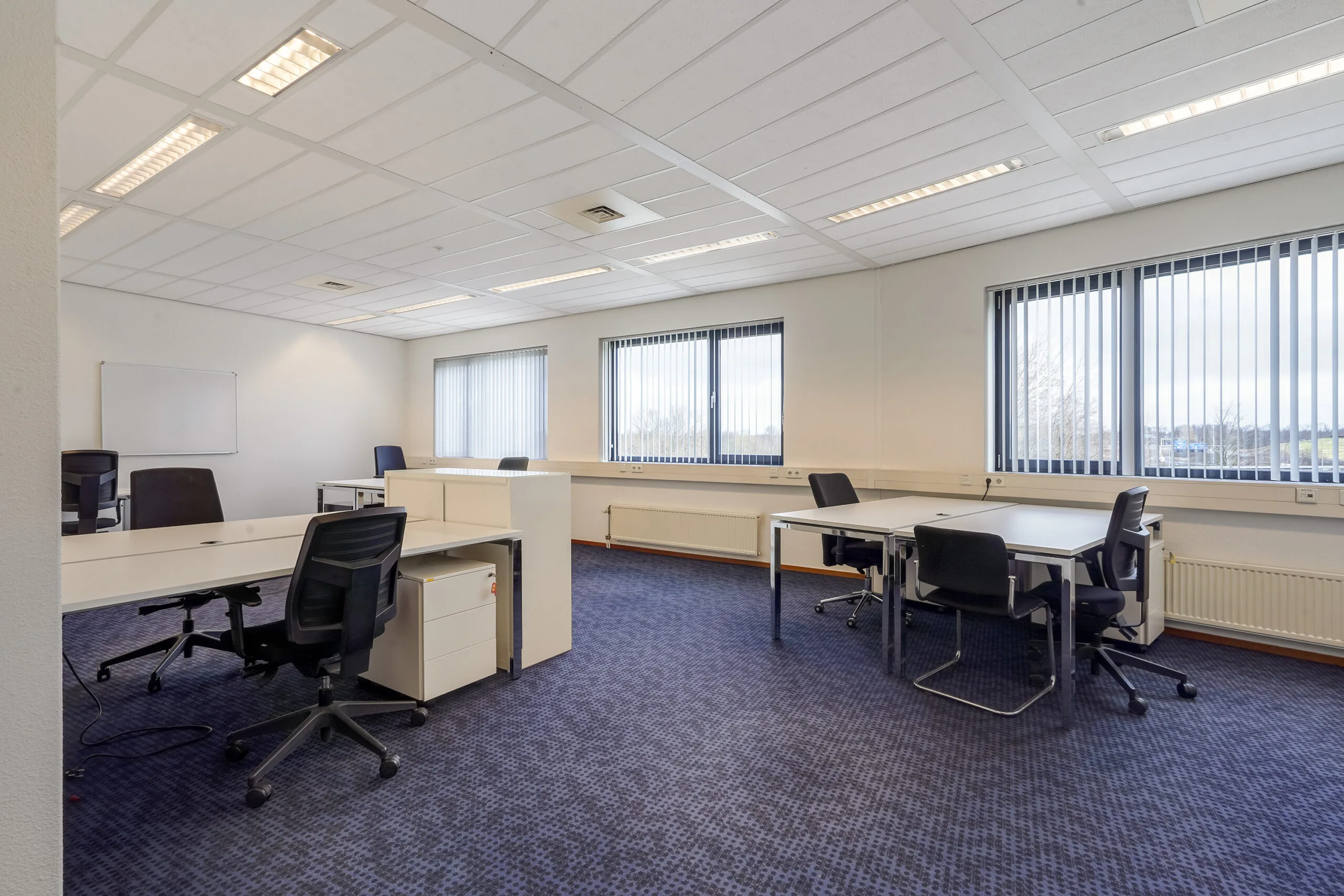 Lichte, moderne kantoorkamer aan de Laan van ’s-Gravenmade met meerdere bureaus en bureaustoelen.