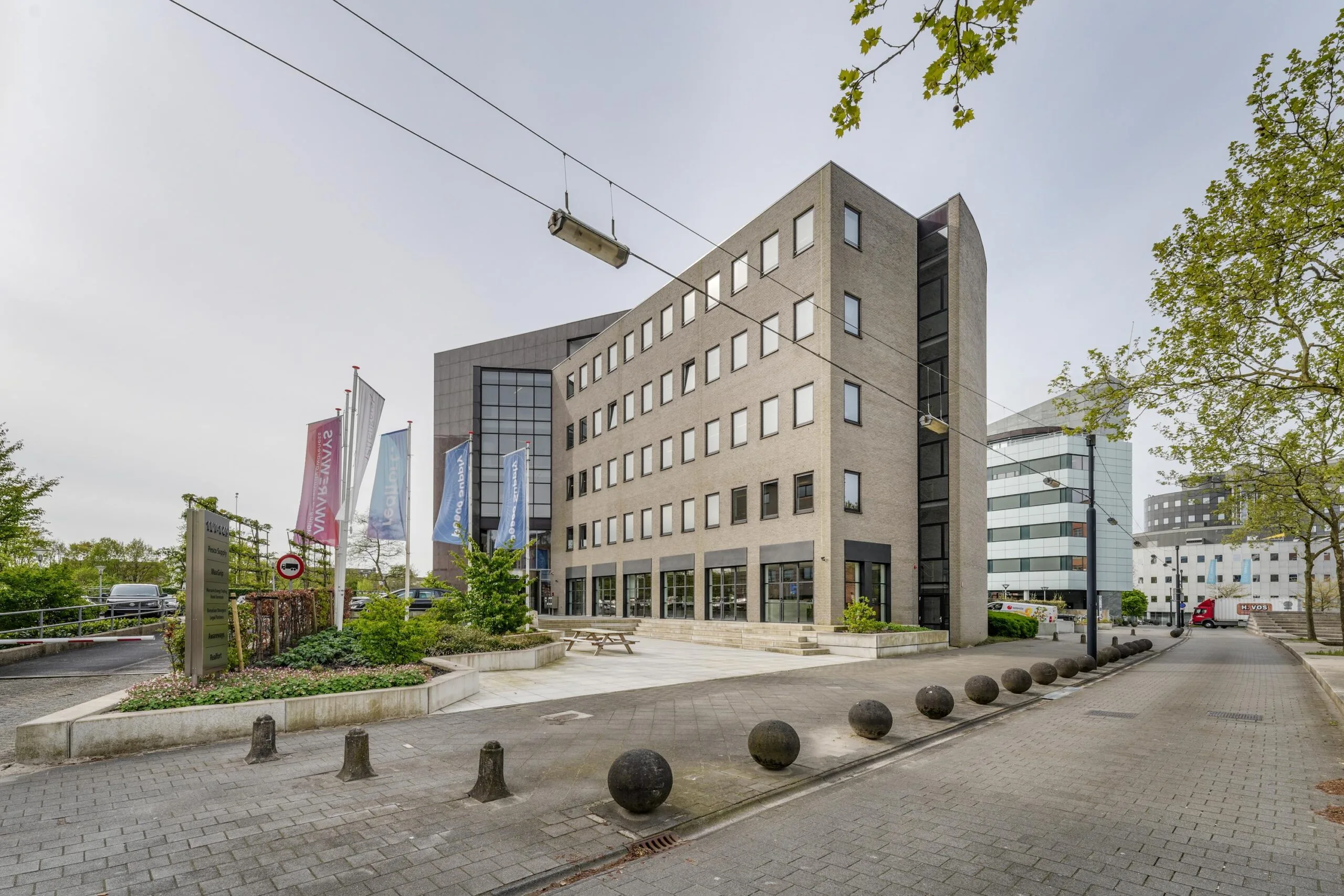 Voorzijde van een modern kantoorgebouw aan de Euclideslaan in Utrecht met vlaggen en bestrate entree.