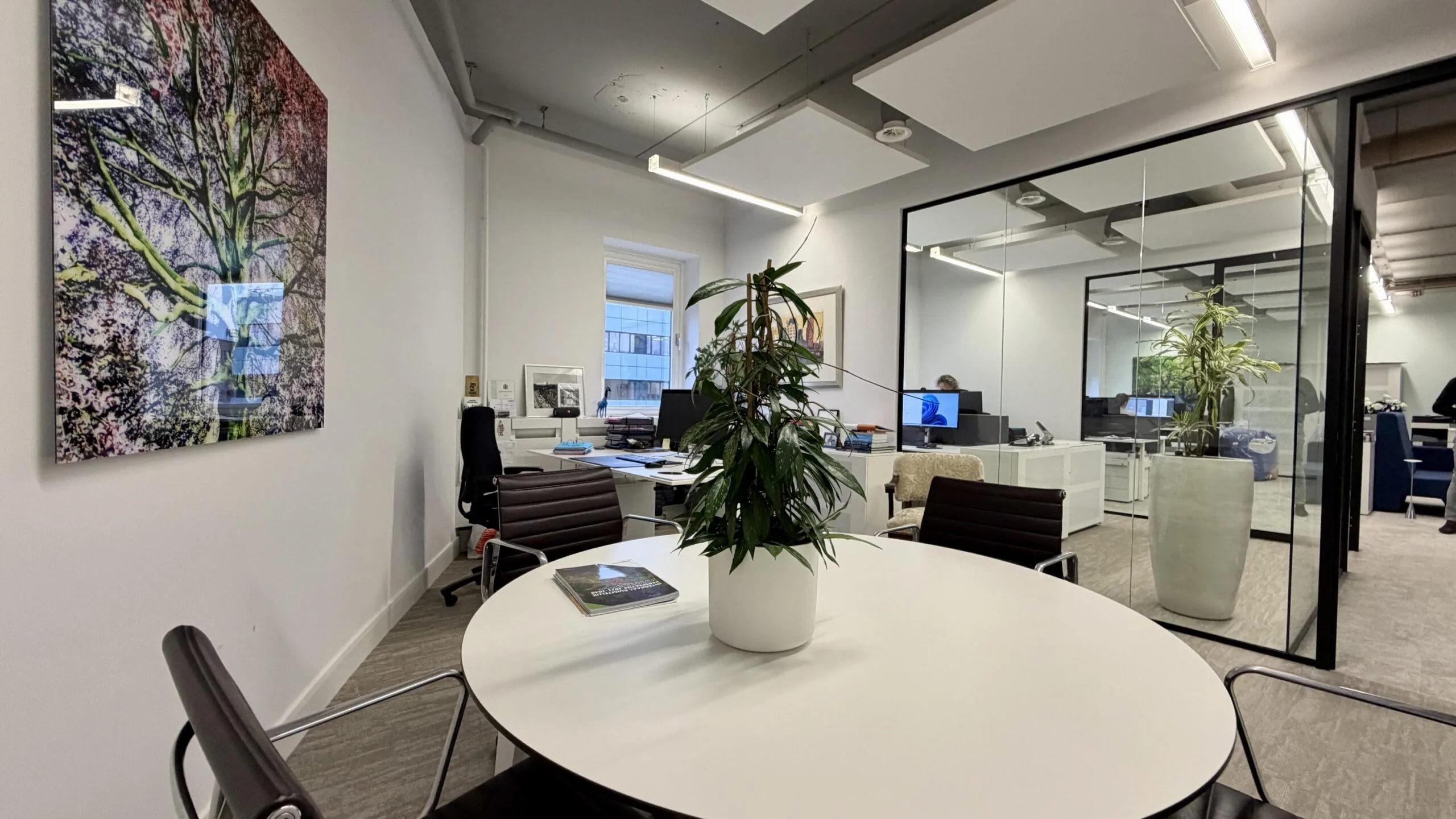 Moderne kantoorruimte aan de Euclideslaan met vergadertafel, bureaus, kamerplanten en glazen wanden.