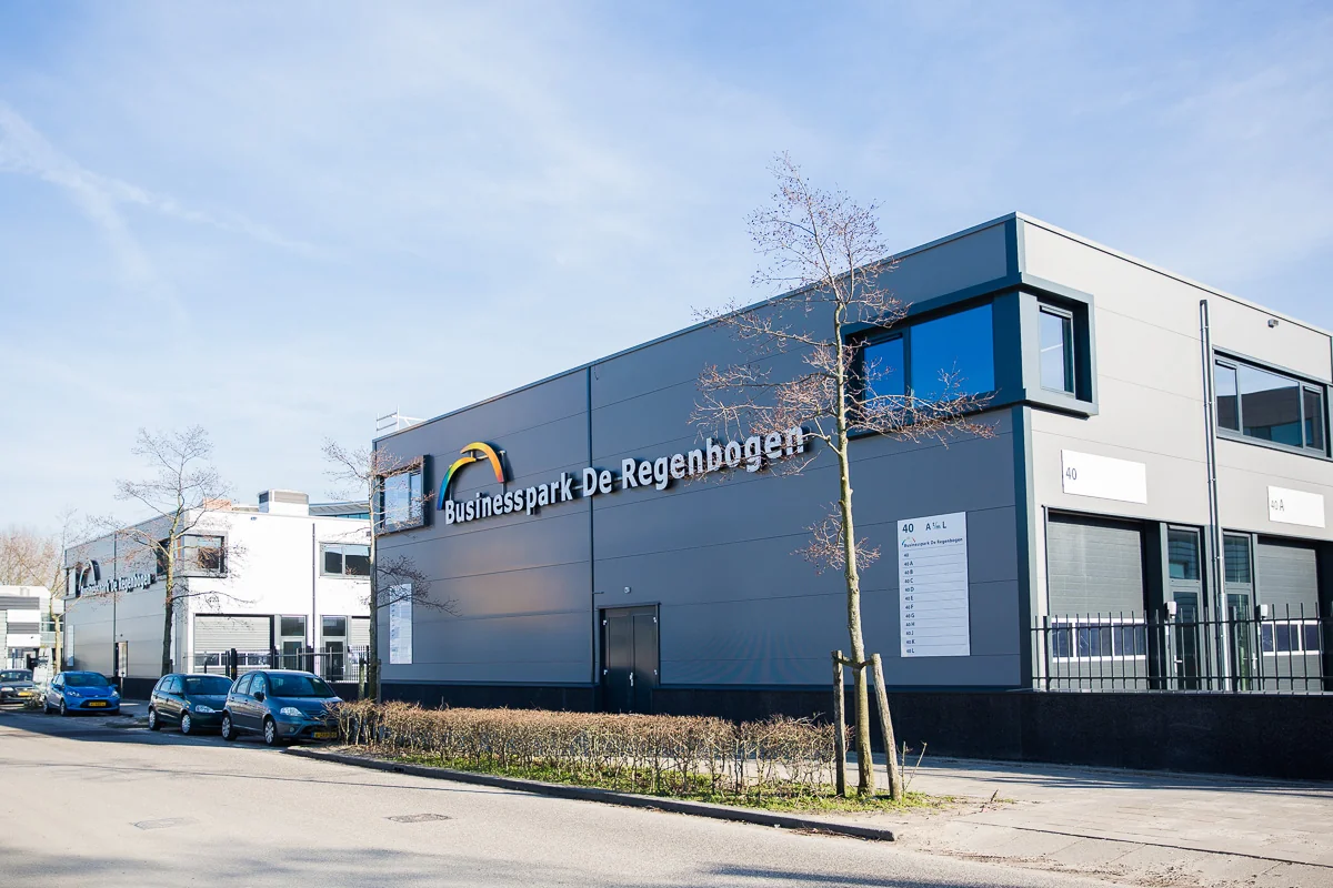 Bedrijfsgebouw aan de Laan van s-Gravenmade met het opschrift "Businesspark De Regenboog" op een zonnige dag.