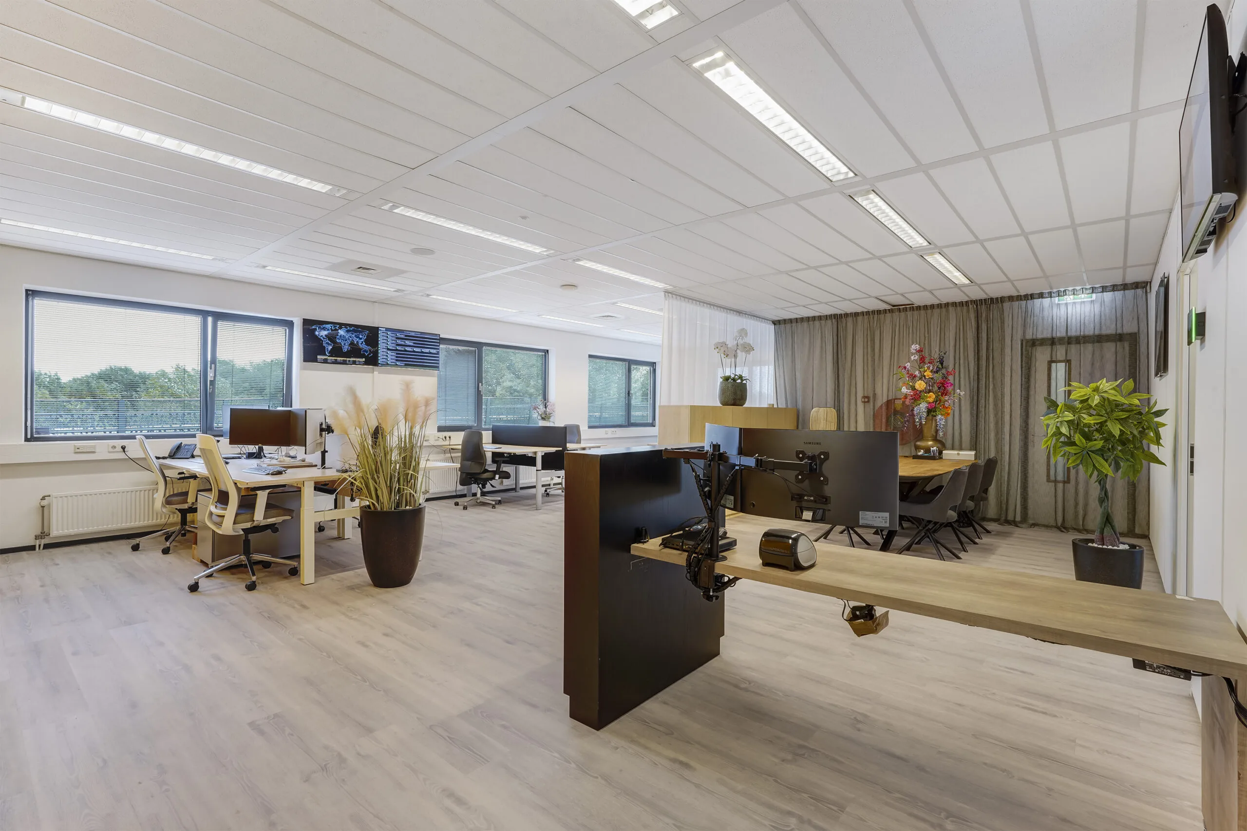 Modern en licht kantoorinterieur aan de Laan van 's-Gravenmade met bureaus, grote ramen en decoratieve planten.