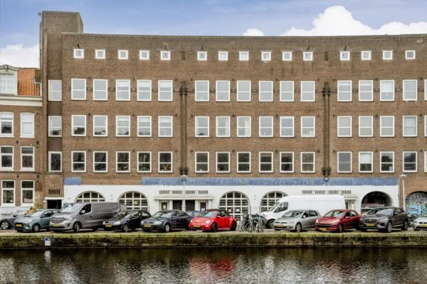 Appartementencomplex aan de Baarsjesweg in Amsterdam met geparkeerde auto's langs de gracht.