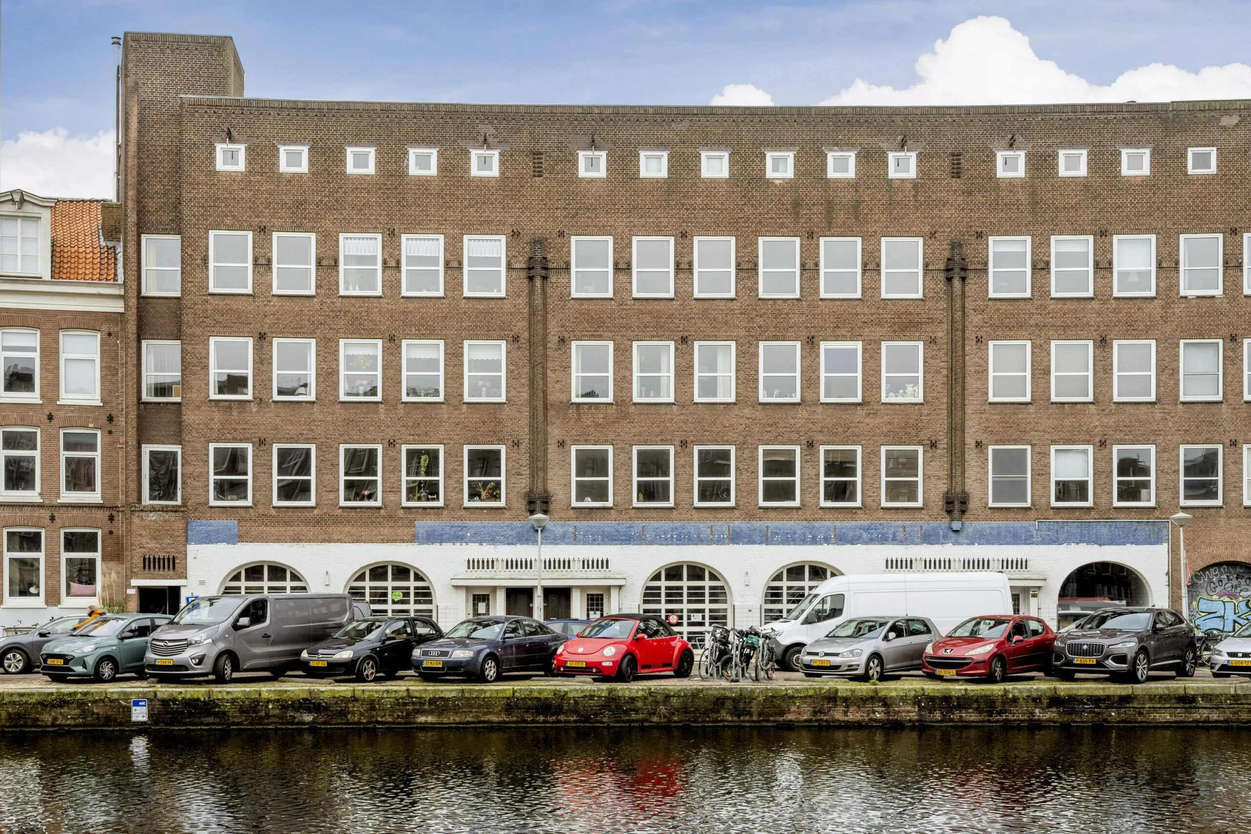 Appartementencomplex aan de Baarsjesweg in Amsterdam met geparkeerde auto's langs de gracht.