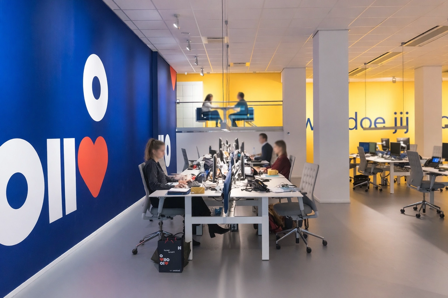 Modern kantoorinterieur aan de Vijzelstraat met open werkplekken, kleurrijke muren en medewerkers achter computers.