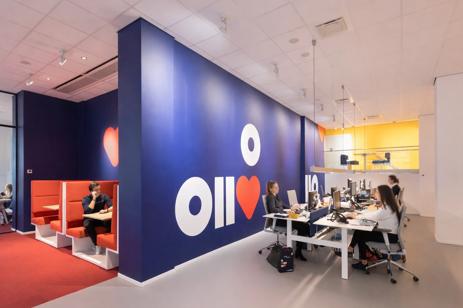 Moderne kantoorruimte aan de Vijzelstraat met open werkplekken, vergadernissen en een blauwe muur met opvallende grafische elementen.