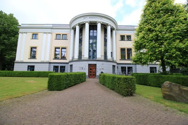 Vooraanzicht van het statige gebouw 'Het Hoogeland' aan de Museumlaan, omgeven door een verzorgde tuin met heggen en bomen.